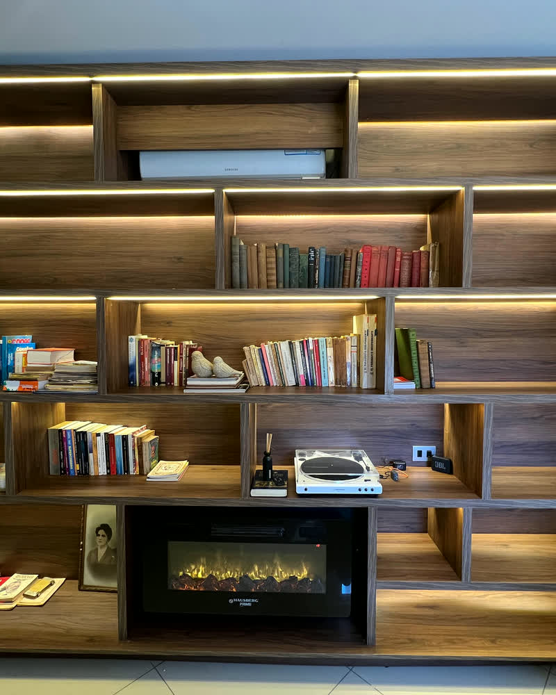 Biblioteca de madera con estantes iluminados y hogar eléctrico
